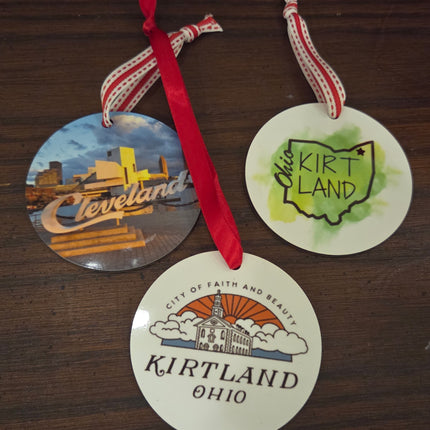 Three round stickers with 'Cleveland', 'Kirtland Ohio', and a map of Kirtland Ohio design on a wooden surface.