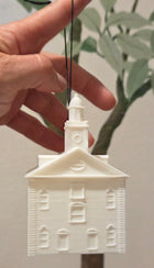 Hand holding a small white architectural model of a building against a neutral background