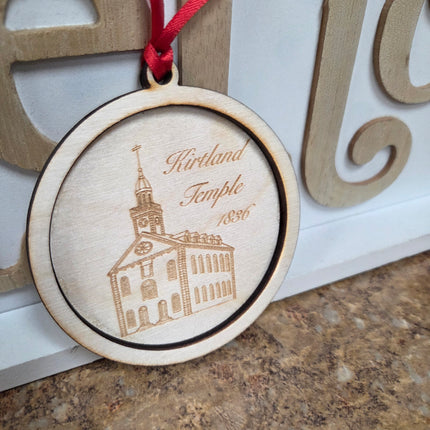 Wooden ornament with engraved design and red ribbon on a textured surface