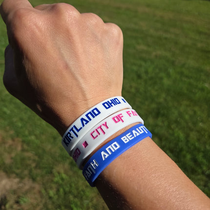 Wrist with multiple colorful wristbands on a grassy background